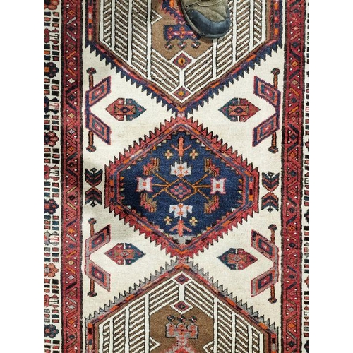 1032 - North West Persian Heriz cream ground runner with central lozenge medallion flanked by two larger ge... 