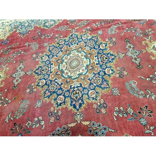 1057 - North East Persian Signed red ground Meshed carpet with large centralised floral medallion enclosed ... 