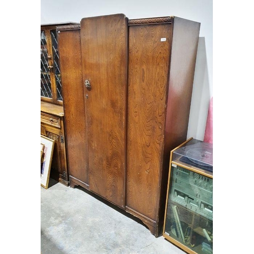 1142 - Dark stained oak wardrobe with flowerhead moulded frieze above rounded central door, enclosing a she... 