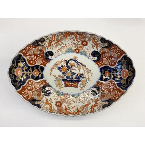 122 - Japanese Imari porcelain dish, oval and scalloped, centred by boughpot and having phoenix and brocad... 