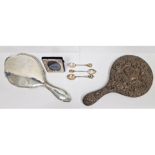 303 - Two silver backed dressing mirrors, one repousse decorated, a miniature silver mounted picture frame... 