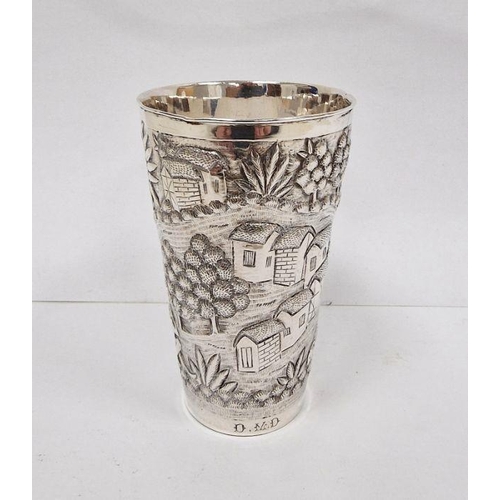 379 - Foreign silver-coloured metal cup with relief of village and figures, initialled to base 'D.M.D', un... 