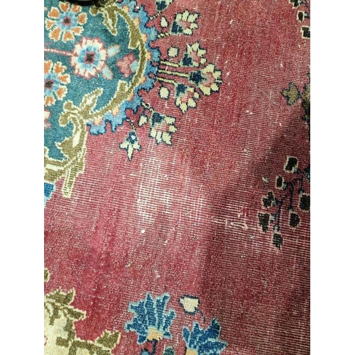 1053 - North East Persian signed red ground Meshed carpet with large centralised floral medallion enclosed ... 