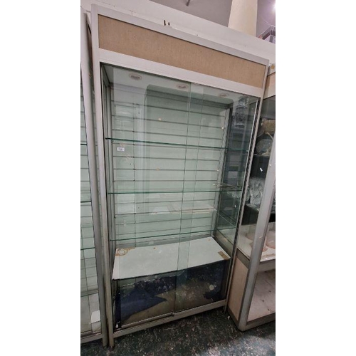 1066 - Two large glazed display cabinets each having glass sliding doors, one with four glass shelves, the ... 