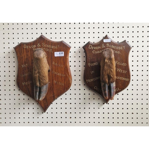 235 - Two taxidermy deer stag hooves, each on inscribed oak wall mounts, the first named for Devon and Som... 