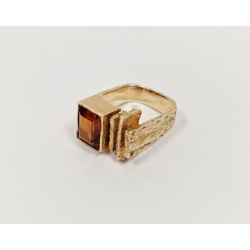 574 - 14K gold and orange stone ring of modernist form set rectangular single stone in stepped bark-patter... 