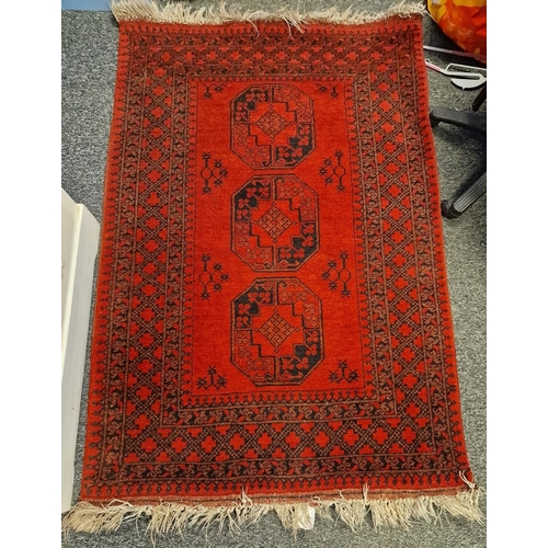 1272 - Middle Eastern red ground wool rug decorated with three octagonal guls, within a geometric pattern b... 