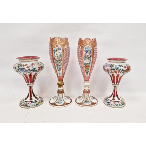 64 - Two pairs of late 19th century Bohemian ruby tinted cased and enamelled vases, the first tapering ov... 