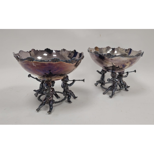 253 - Pair silver-plated pedestal bowls, each with scroll and shell border, on three putto supports, each ... 