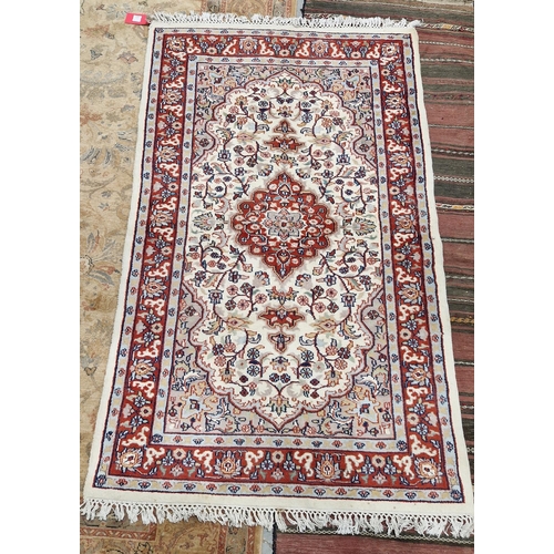 1191 - Indian cream ground wool pile rug, central floral medallion within stylised floral panel with spandr... 