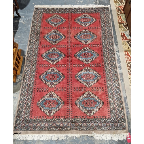 1195 - Turkish-style red ground wool rug, central panel with two rows of five geometric stepped lozenges in... 