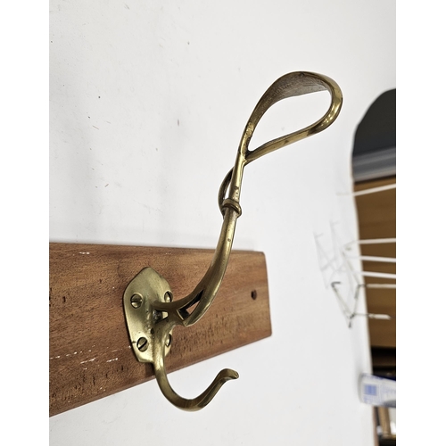 127 - Set of four Art Nouveau brass coat hooks of entwined tendril form, later mounted on a teak plank, 91... 