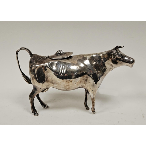 568 - A Elizabeth II silver cow creamer, the hinged lid applied with a fly finial, the tail forming a hand... 