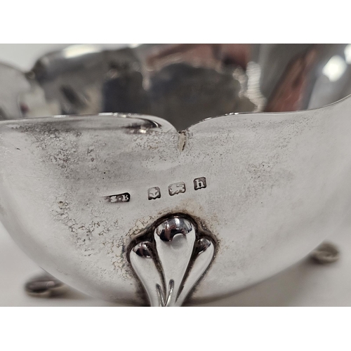 588 - An Edwardian silver cream jug, of plain form, scalloped edge, raised on three pad feet, scroll handl... 