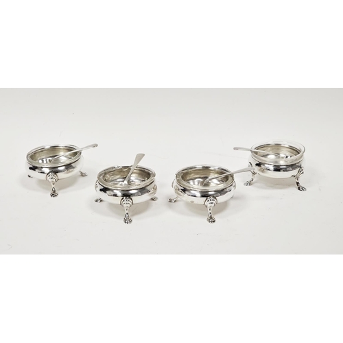 609 - A set of four George V circular silver open salts, with clear glass liners and spoons, raised on thr... 