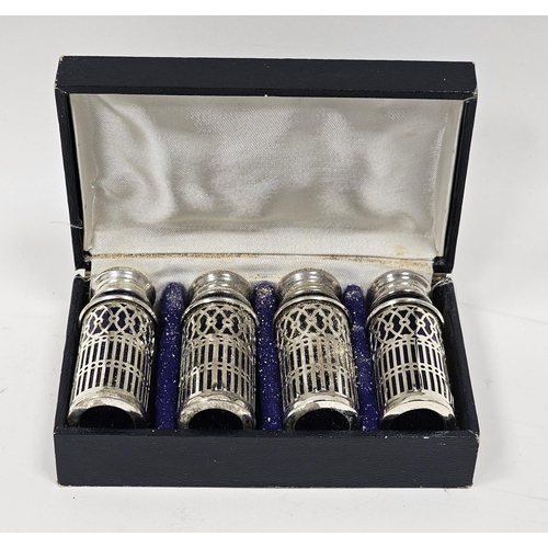 622 - A set of four silver plated pepperettes, on a pierced lattice decoration, blue glass liners, in fitt... 