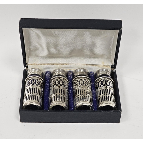 622 - A set of four silver plated pepperettes, on a pierced lattice decoration, blue glass liners, in fitt... 