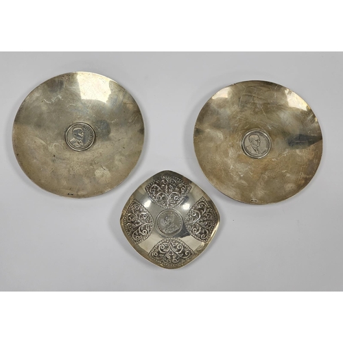 648 - A pair of South African silver-coloured metal circular footed dishes, both inset with a 1969 one Ran... 