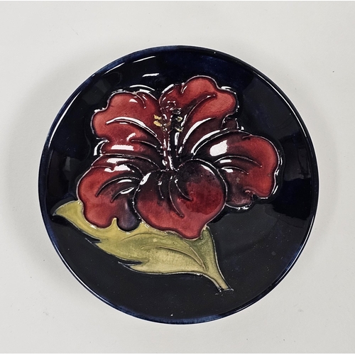 67 - Moorcroft blue ground small circular dish in the Hibiscus pattern, marks below Potters to the Late Q... 