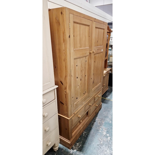 1021 - 20th century pine wardrobe, the double panel doors opening to a hanging space, over an arrangement o... 