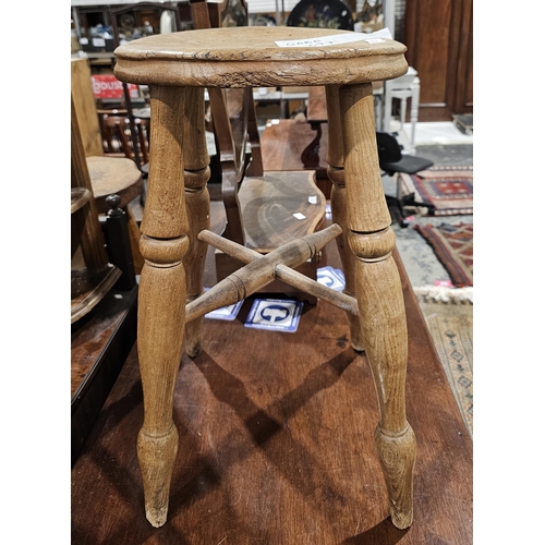 1091 - Late 19th/early 20th century rustic elm stool, the circular seat raised on turned legs united by cro... 