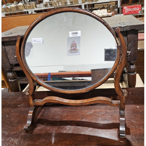 1096 - An early 20th century mahogany oval swing mirror held on a slender frame 39cm wide by 39cm high