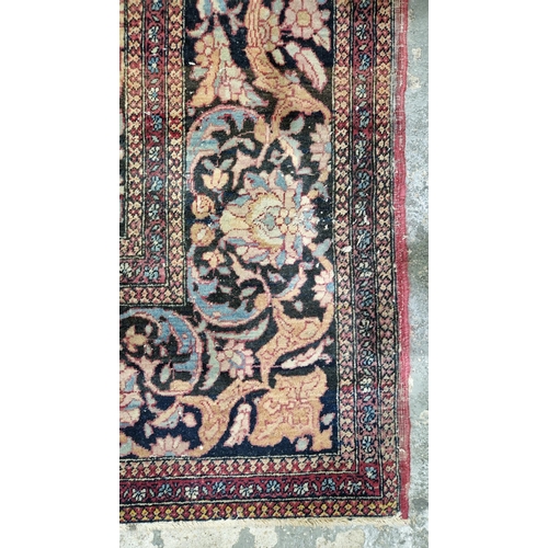 1212 - Eastern wool rug of Persian design, having black arabesque to the cherry red field with allover flor... 