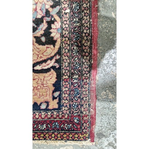 1212 - Eastern wool rug of Persian design, having black arabesque to the cherry red field with allover flor... 