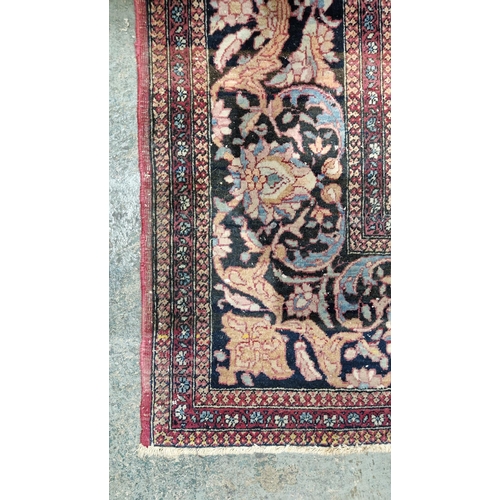 1212 - Eastern wool rug of Persian design, having black arabesque to the cherry red field with allover flor... 