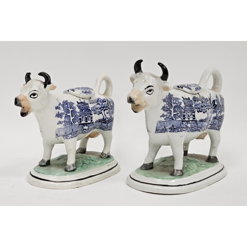 55 - Two 19th century Staffordshire pottery cow creamers with blue transfer willow pattern standing on gr... 