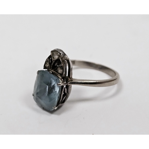 683 - White metal and pale blue stone solitaire ring, the cushion shape stone topped by a trio of three ti... 