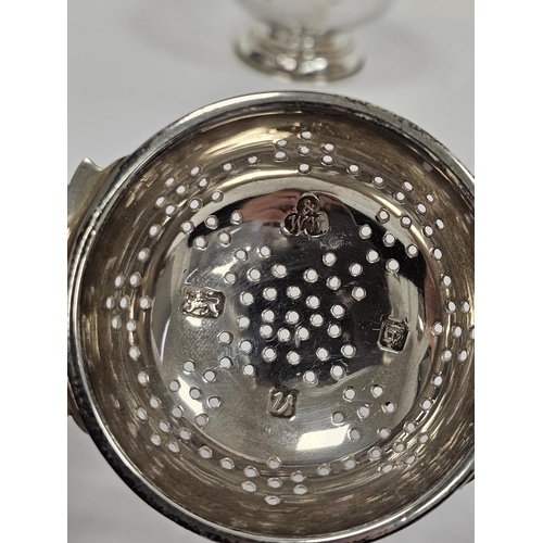 302a - Silver tea strainer, London 1995, Wakely & Wheeler, with ornate pierced twin handles and plain bodie... 