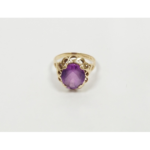 492 - 14K gold and purple stone ring, the oval stone in scroll bordered mount (size P)