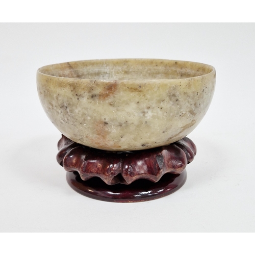 101 - Chinese soapstone bowl, of cup-form, raised on four stilt feet, on wooden stand 13cm diam.