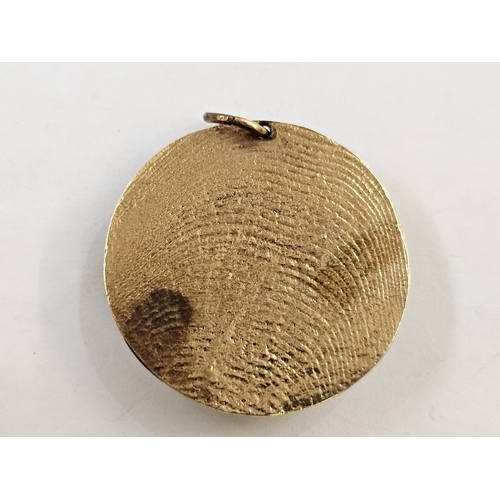 504 - Yellow metal pendant of circular form, modelled with a lion's head on a textured ground, unmarked (t... 