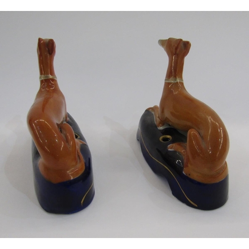 52 - Pair of Staffordshire pottery greyhound pen rests, each ochre coloured hound seated on a dark blue m... 