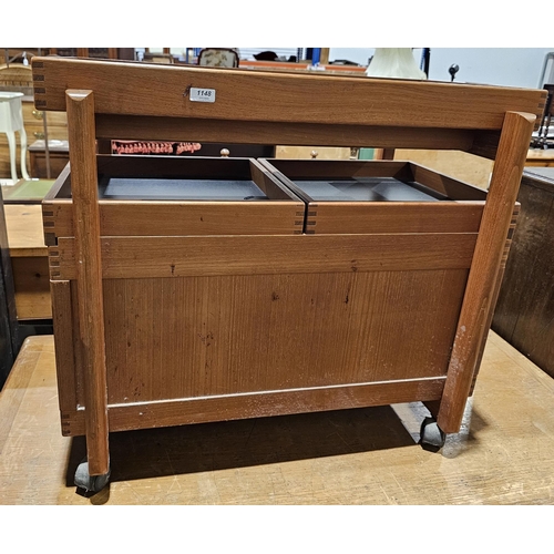 1148 - Mid-century teak storage trolley, with two sliding shelves opening to a storage compartment, on cast... 