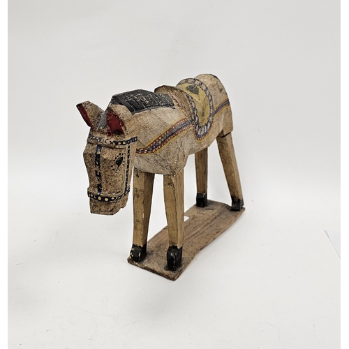 145 - Folk Art hand carved and painted model of a horse or donkey, wearing a saddle, on a plank base, 46cm... 