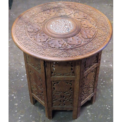 114 - 20th century heavily carved Indian style folding occasional table. App. 55cm H x 54cm Diameter