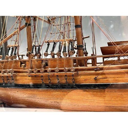 101 - A wooden model of HMS Bounty, with deck fittings, on a stand, in a perspex display case, overall dim... 