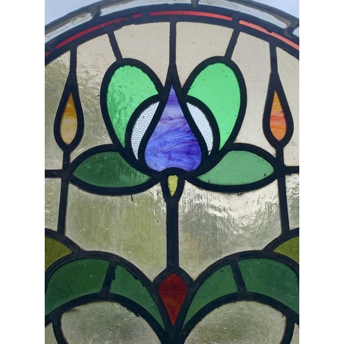 141 - An early 20th century leaded and stained glass panel of arched form. Height 45cm, width 59cm.