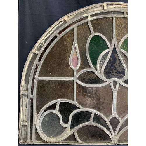 141 - An early 20th century leaded and stained glass panel of arched form. Height 45cm, width 59cm.