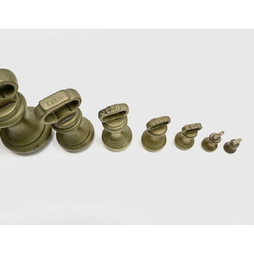 144 - A group of nine brass bell weights, 7LB to 1/2OZ, the biggest height 18.5cm, together with a nest of... 