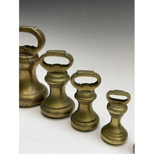 144 - A group of nine brass bell weights, 7LB to 1/2OZ, the biggest height 18.5cm, together with a nest of... 