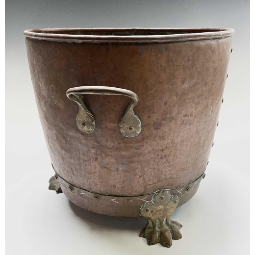 242 - A copper log bin, circa 1920, with twin handles and raised on brass paw feet, height 31cm, diameter ... 