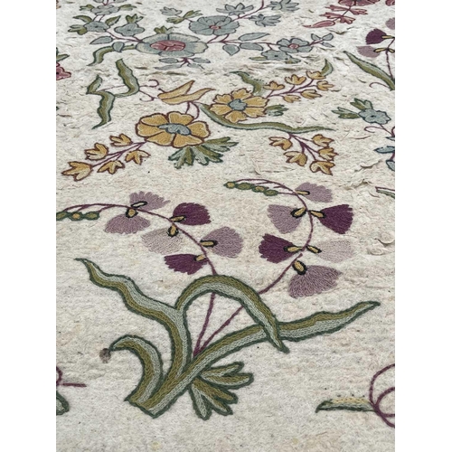 2800 - A cream ground rug/wall hanging with floral crewelwork decoration. 177 x 118.5cm.