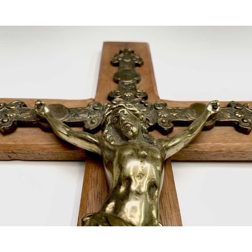 284 - A mid century oak mounted cast brass wall hanging crucifix. Overall height 47.5cm.