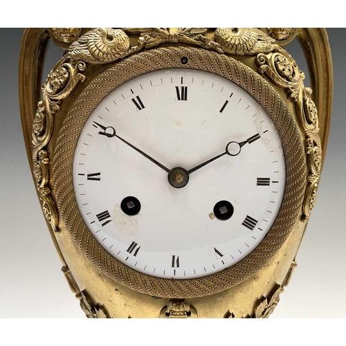 2918 - A French Empire ormolu cased mantel clock, of urn form, the covered rim applied with two winged cher... 