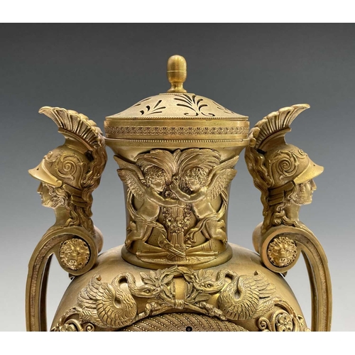 2918 - A French Empire ormolu cased mantel clock, of urn form, the covered rim applied with two winged cher... 