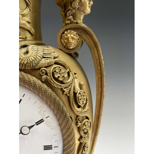 2918 - A French Empire ormolu cased mantel clock, of urn form, the covered rim applied with two winged cher... 